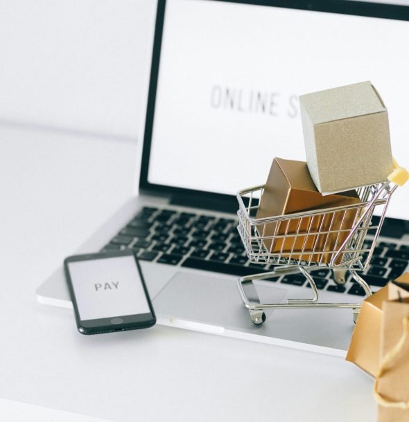 Mini shopping cart on laptop symbolizing online shopping and e-commerce transactions.
